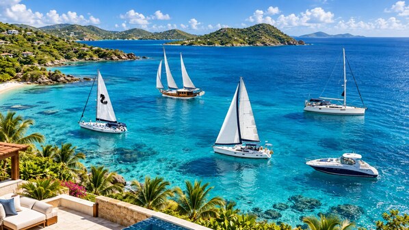 A coastal view with multiple sailboats on clear turquoise waters, surrounded by lush greenery and hills.