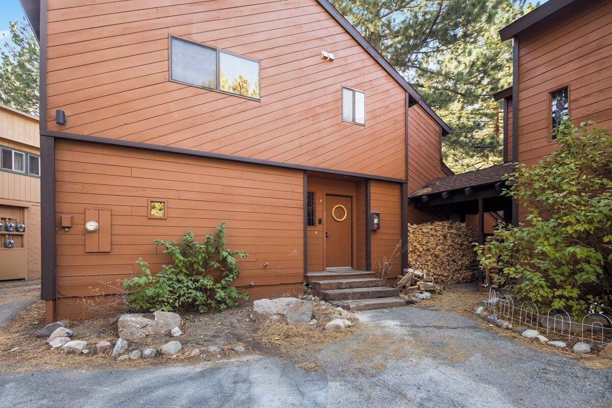 A two-story wooden building with a front door, a small window, and a stone pathway leading to the entrance.