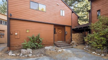 A two-story wooden building with a front door, a small window, and a stone pathway leading to the entrance.