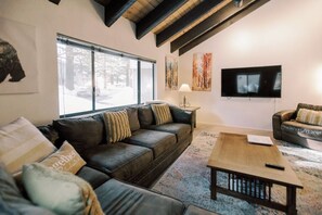 A living room with a sofa, a coffee table, and a television.