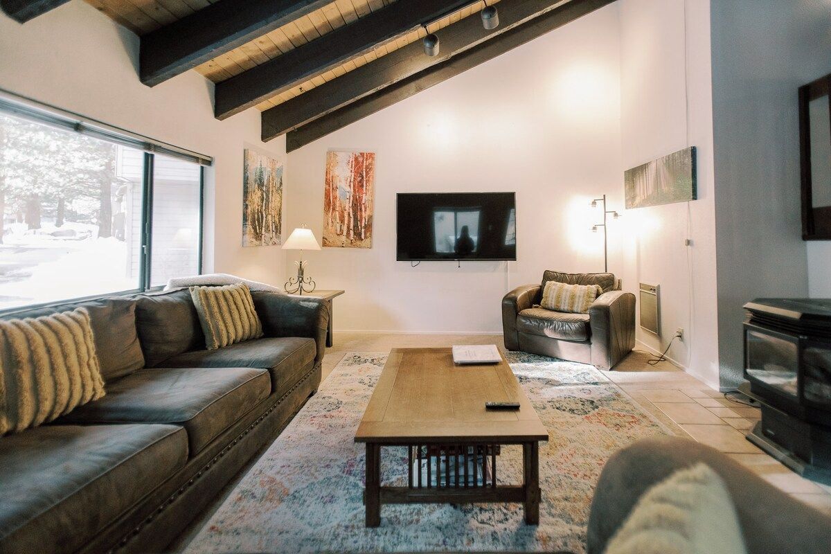 A living room with a sofa, a coffee table, a television, and a fireplace.