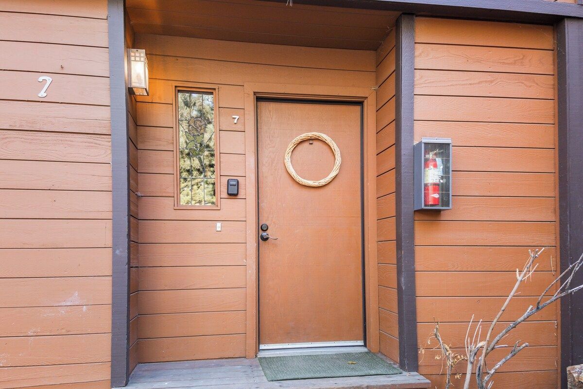 A wooden door with a circular wreath, a small window, and a doorbell.