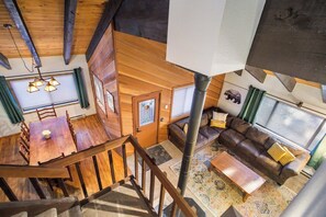 A wooden interior with a dining area, a sofa, and a staircase.