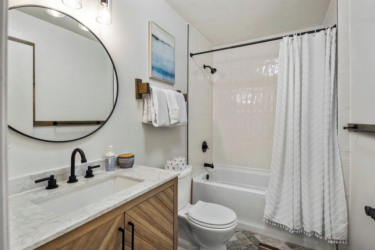 A bathroom with a white sink, a mirror, a toilet, and a shower curtain.