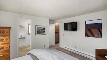 A bedroom with a bed, a dresser with animal carvings, a television on the wall, and a picture frame.