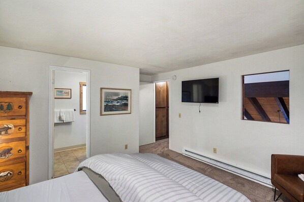 A bedroom with a bed, a dresser with animal carvings, a television on the wall, and a picture frame.