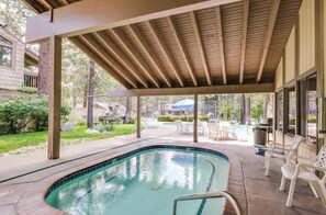 A covered outdoor swimming pool with a wooden ceiling, surrounded by lounge chairs and a patio area. - Mammoth Horizon 4 1BD 1BA Family Getaway (Mammoth Lakes)