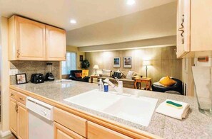 A compact kitchen with a large countertop, wooden cabinets, and a dishwasher. - Mammoth Horizon 4 1BD 1BA Family Getaway (Mammoth Lakes)