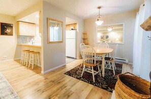 A dining area with a round table, white chairs, and a patterned rug. - Mammoth Horizon 4 1BD 1BA Family Getaway (Mammoth Lakes)