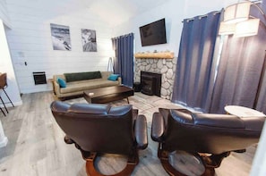A living room with a sofa, two leather chairs, a fireplace, and a television mounted on the wall. - Pet Friendly 1BR loft 2BA Modern Mammoth Condo (Mammoth Lakes)