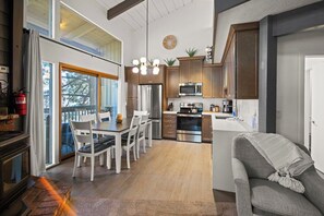 A modern kitchen with a dining area, a fireplace, and a view of the outdoors. - Mammoth Mountain 3BR 3BA Beautiful Family Getaway (Mammoth Lakes)