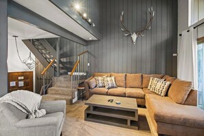 A modern living room with a sofa, coffee table, and a staircase. - Mammoth Mountain 3BR 3BA Beautiful Family Getaway (Mammoth Lakes)
