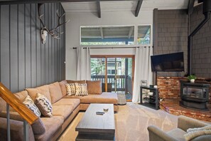 A modern living room with a sofa, coffee table, and fireplace. - Mammoth Mountain 3BR 3BA Beautiful Family Getaway (Mammoth Lakes)