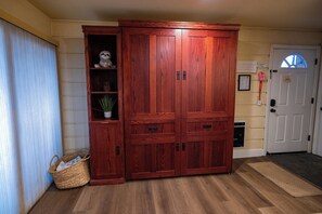 A wooden cabinet with multiple drawers and shelves, a basket, and a door with a window. - Pet Friendly 1BD 1BA Mammoth Retreat (Mammoth Lakes)
