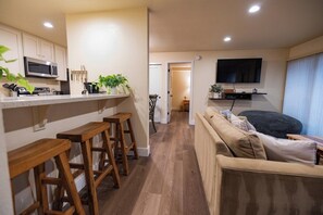 A modern kitchen with wooden stools, a microwave, and a TV mounted above the counter. - Pet Friendly 1BD 1BA Mammoth Retreat (Mammoth Lakes)