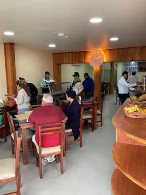 Un restaurante con muebles de madera y una barra central con frutas.