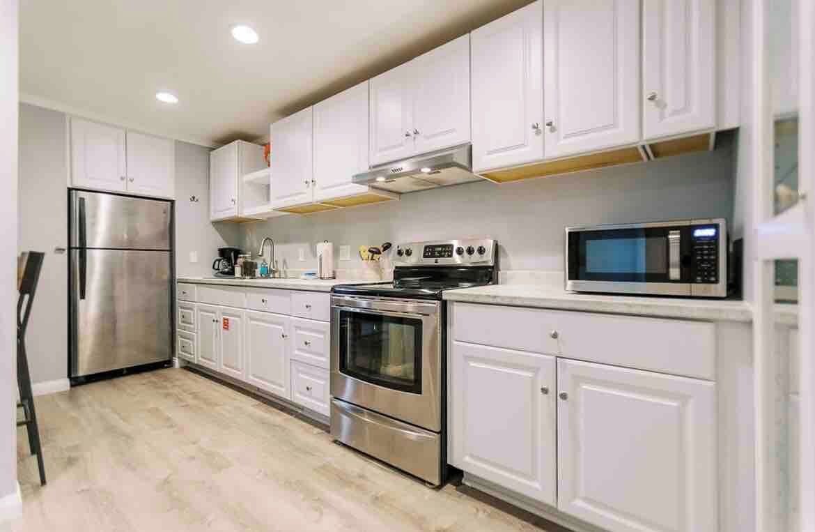 A kitchen with white cabinets, stainless steel appliances, and a microwave.