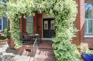 A brick building with a black door, a bench, and a sign that reads 'SMILE YOU RECONCILE'. - The Lyons Estate | Historic Savannah Luxury (Savannah)