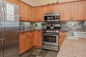 A kitchen with wooden cabinets, stainless steel appliances, granite countertops, and a stone backsplash. - Pet Friendly Mammoth Cabin Gorgeous Views 2bd 2ba (Mammoth Lakes)