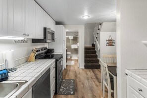 A compact kitchen with white cabinets, a microwave, and a dishwasher. - Village Hidden Valley Family 1bd+Loft (Mammoth Lakes)