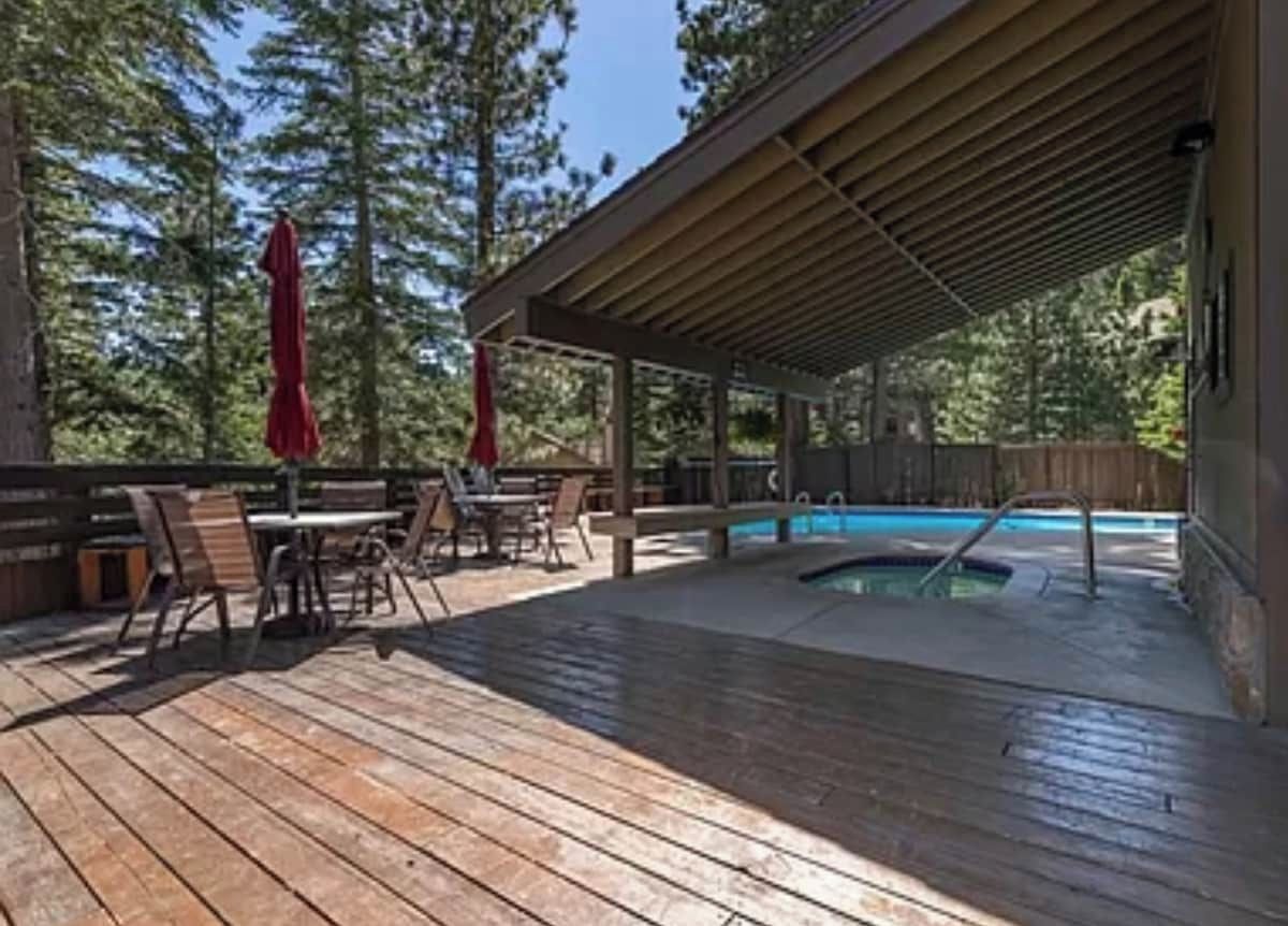 A wooden deck with a pool, outdoor seating, and a covered area.