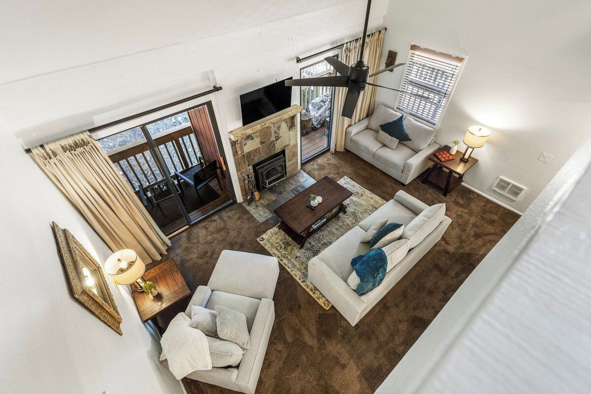 A spacious living room with a fireplace, a television, and a ceiling fan.