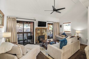 A living room with a fireplace, a ceiling fan, and a TV mounted on the wall. - Village Hidden Valley Family 1bd+Loft (Mammoth Lakes)