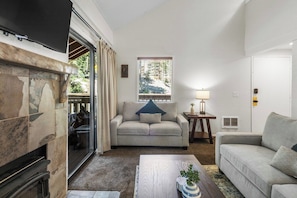 A living room with a fireplace, a sofa, a coffee table, and a window with blinds. - Village Hidden Valley Family 1bd+Loft (Mammoth Lakes)