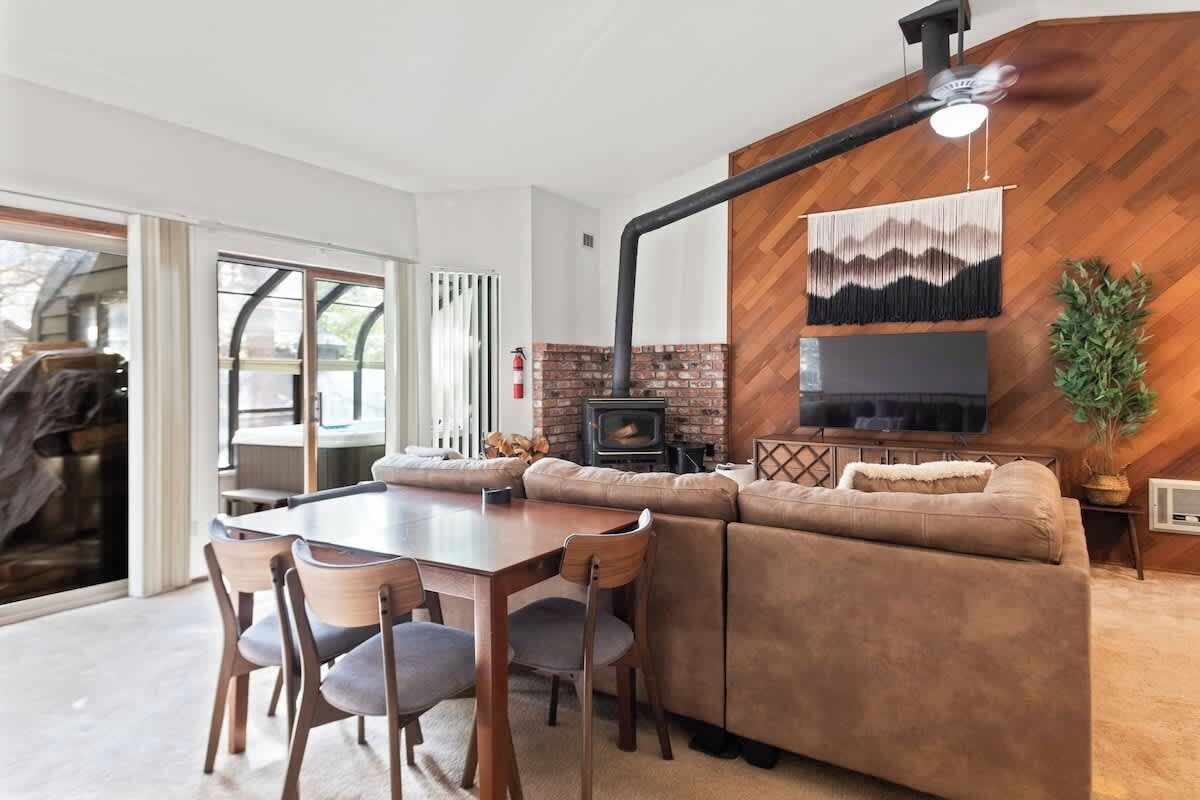 Ein modernes Wohnzimmer mit Kamin, einem an der Wand montierten Fernseher und einem Essbereich mit Tisch und Stühlen.