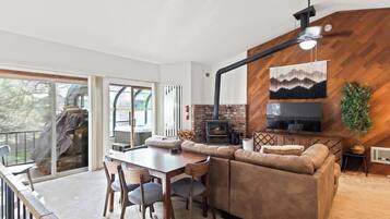 A modern living room with a fireplace, a large TV, and a dining area with a table and chairs.