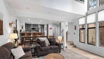 A spacious living area with a sofa, a coffee table, and a dining area in the background.