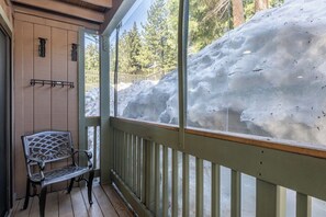 A wooden deck with a metal bench and a snow-covered slope visible through a glass door. - Hidden Valley Studio Walk to Village & Gondola (Mammoth Lakes)