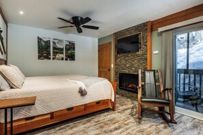 A bedroom with a bed, a fireplace, a chair, and a balcony with a view. - Hidden Valley Studio Walk to Village & Gondola (Mammoth Lakes)