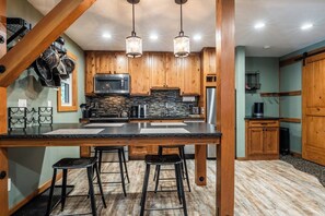 A kitchen with wooden cabinets, a granite countertop, and a bar stool area. - Hidden Valley Studio Walk to Village & Gondola (Mammoth Lakes)