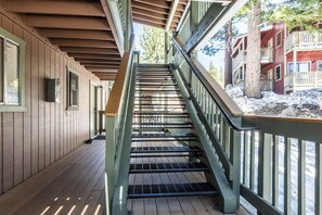 Een houten trap met metalen leuningen die naar een gebouw met meerdere balkons leidt.