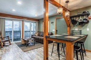 A cozy living area with a wooden dining table, a sofa, and a rocking chair. - Hidden Valley Studio Walk to Village & Gondola (Mammoth Lakes)