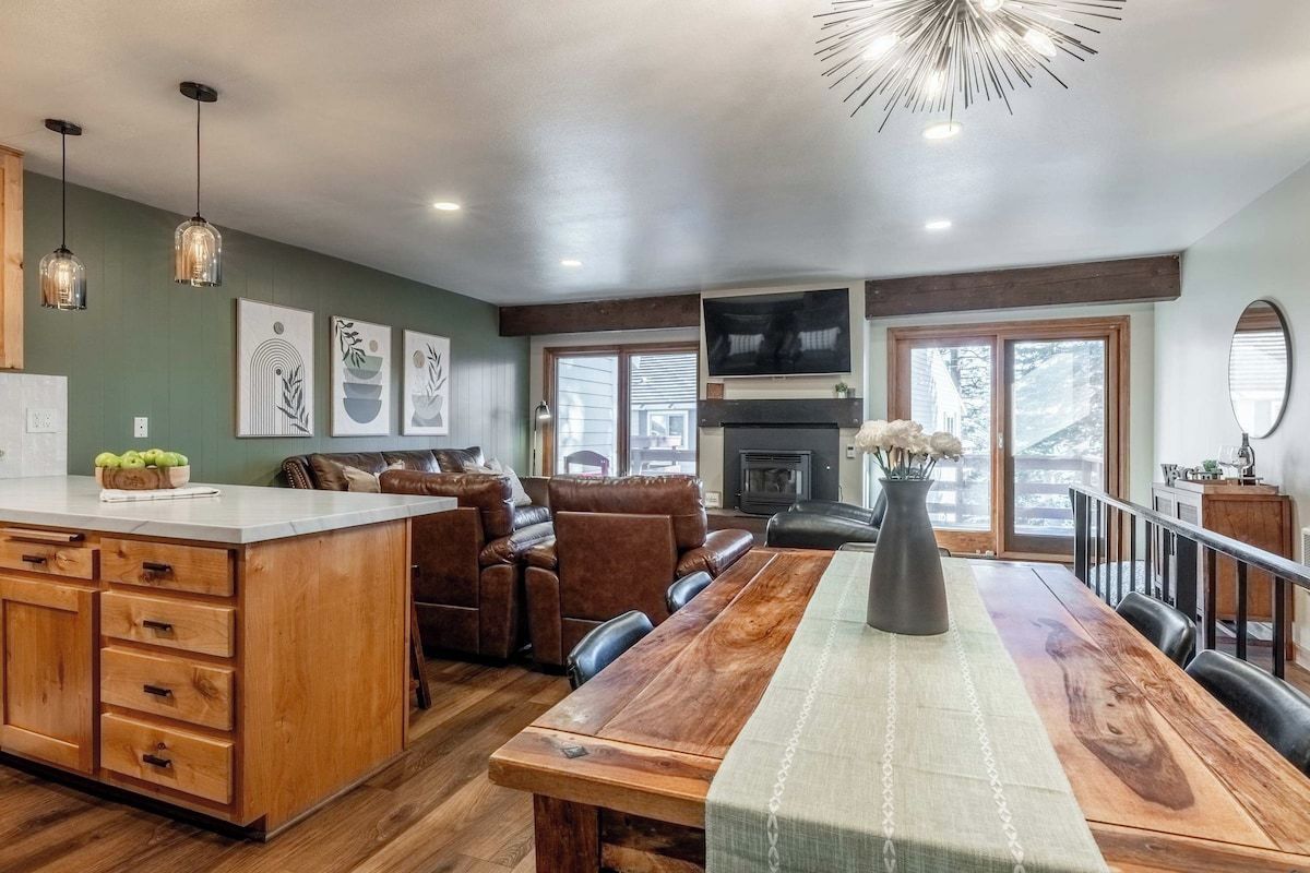 A spacious living area with a wooden dining table, leather sofas, and a fireplace.