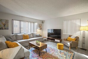 A living room with a sofa, armchair, coffee table, TV, and a patterned rug. - Pet Friendly 2Bd 2.5 Ba Modern Vacation Home (Mammoth Lakes)