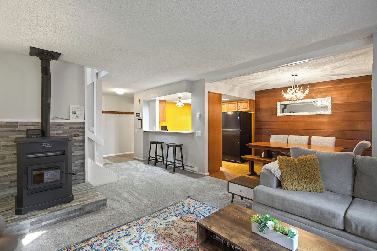 A living room with a fireplace, a sofa, a coffee table, and a dining area with a table and chairs.