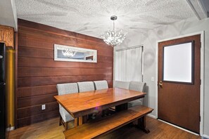 A dining area with a wooden table and benches, a chandelier, and a door with a window. - Pet Friendly 2Bd 2.5 Ba Modern Vacation Home (Mammoth Lakes)