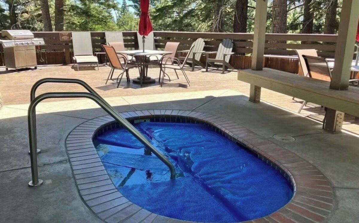 Ein Pool im Freien mit einer Metallleiter, umgeben von einer Holzterrasse, und einem Grillbereich im Hintergrund.