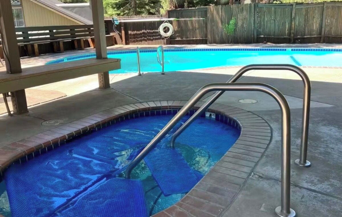 Ein Schwimmbecken mit einer Metallleiter und einer Holzterrasse.