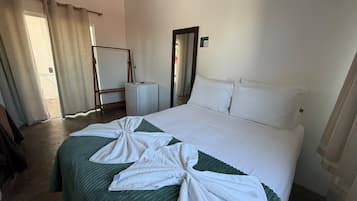 A hotel room with a bed, a bedside table, a mirror, and a door.
