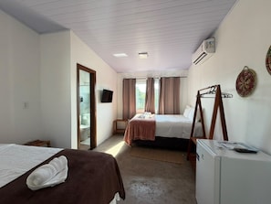 A hotel room with two beds, a small table, a refrigerator, and a television on the wall. - VILA DO RIO (Santo Amaro do Maranhão)