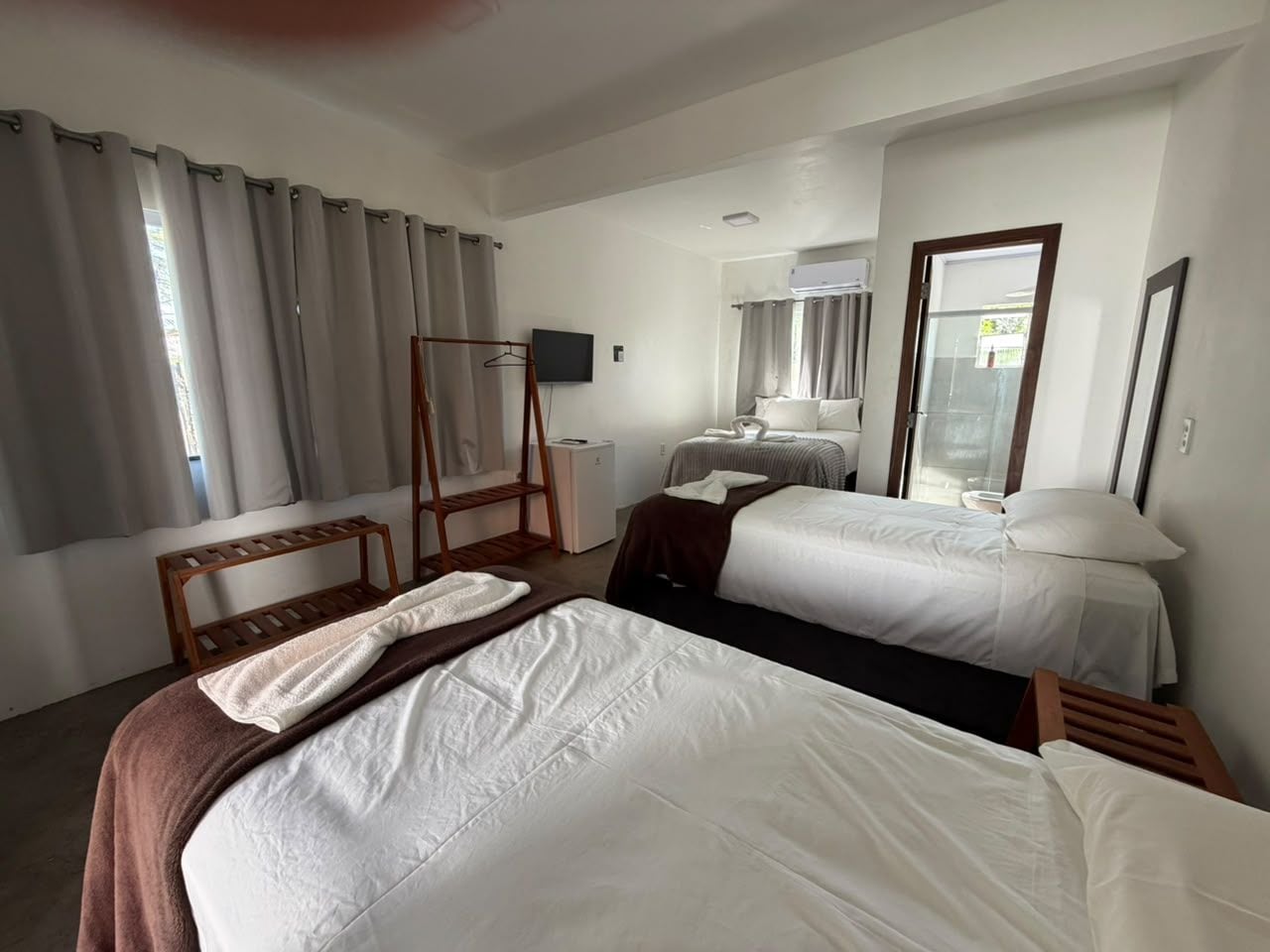 A hotel room with two beds, a wooden chair, a small table, and a television.