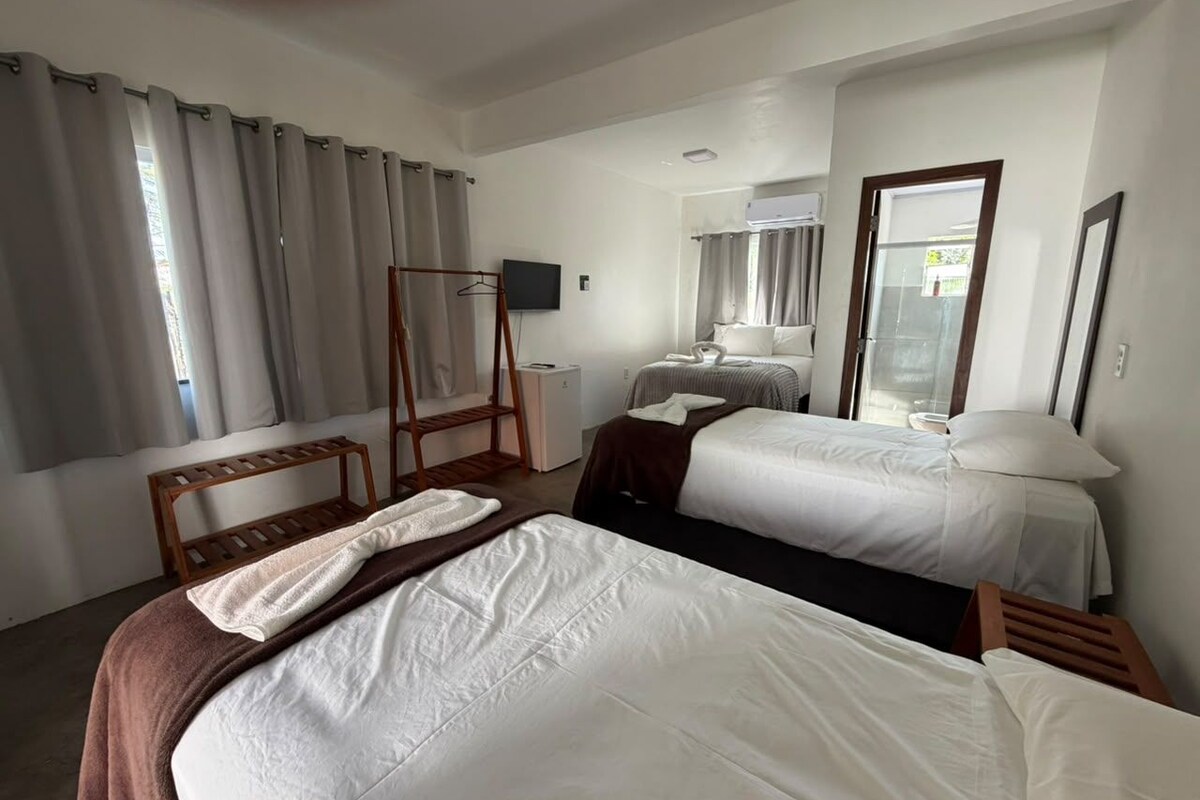 A hotel room with two beds, a wooden chair, a small table, and a television.