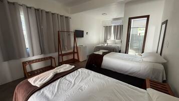 A hotel room with two beds, a wooden chair, a small table, and a television.
