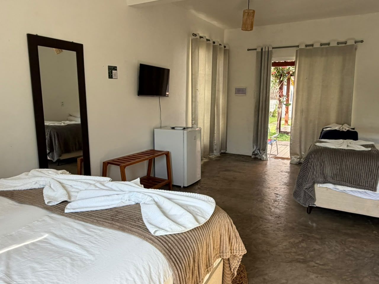 A hotel room with two beds, a television, a small table, and a refrigerator.