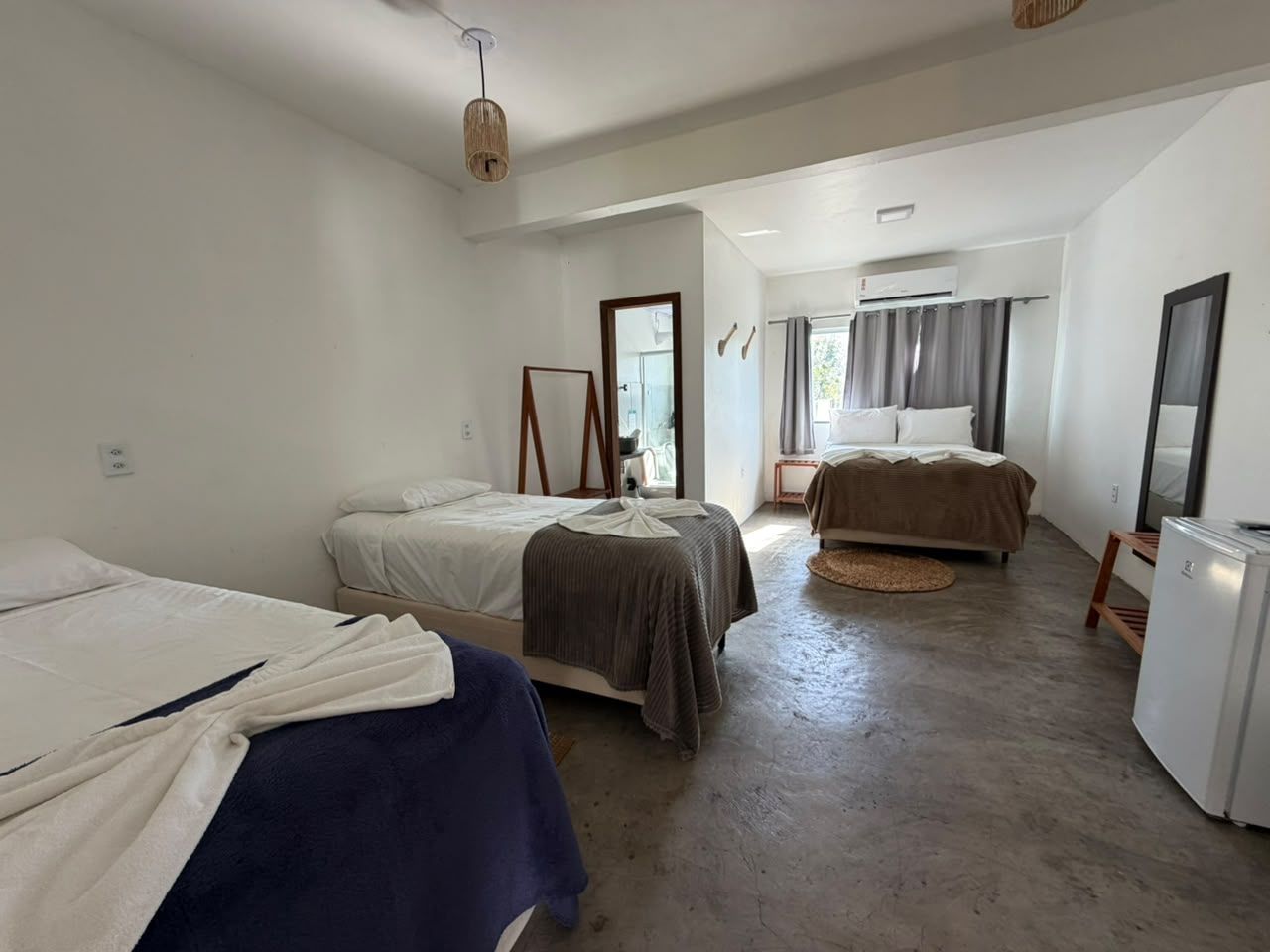 A room with two beds, a refrigerator, and a window with curtains.