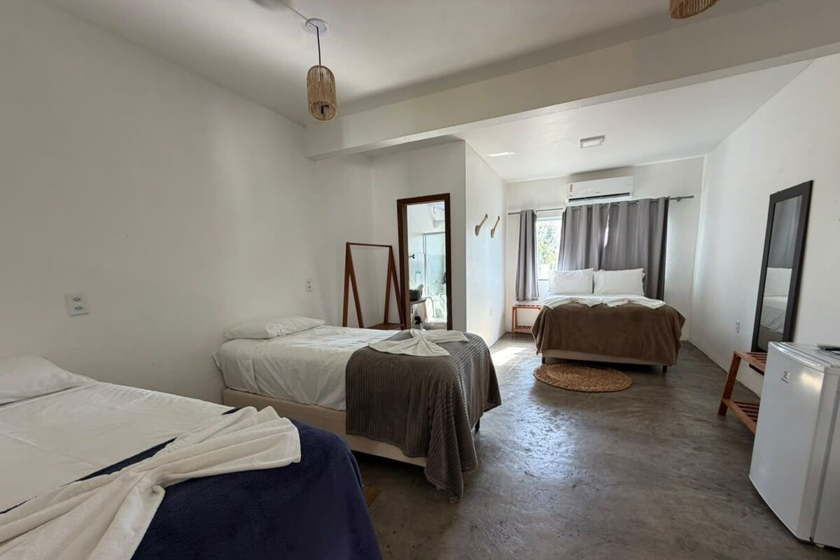 A room with two beds, a refrigerator, and a window with curtains.